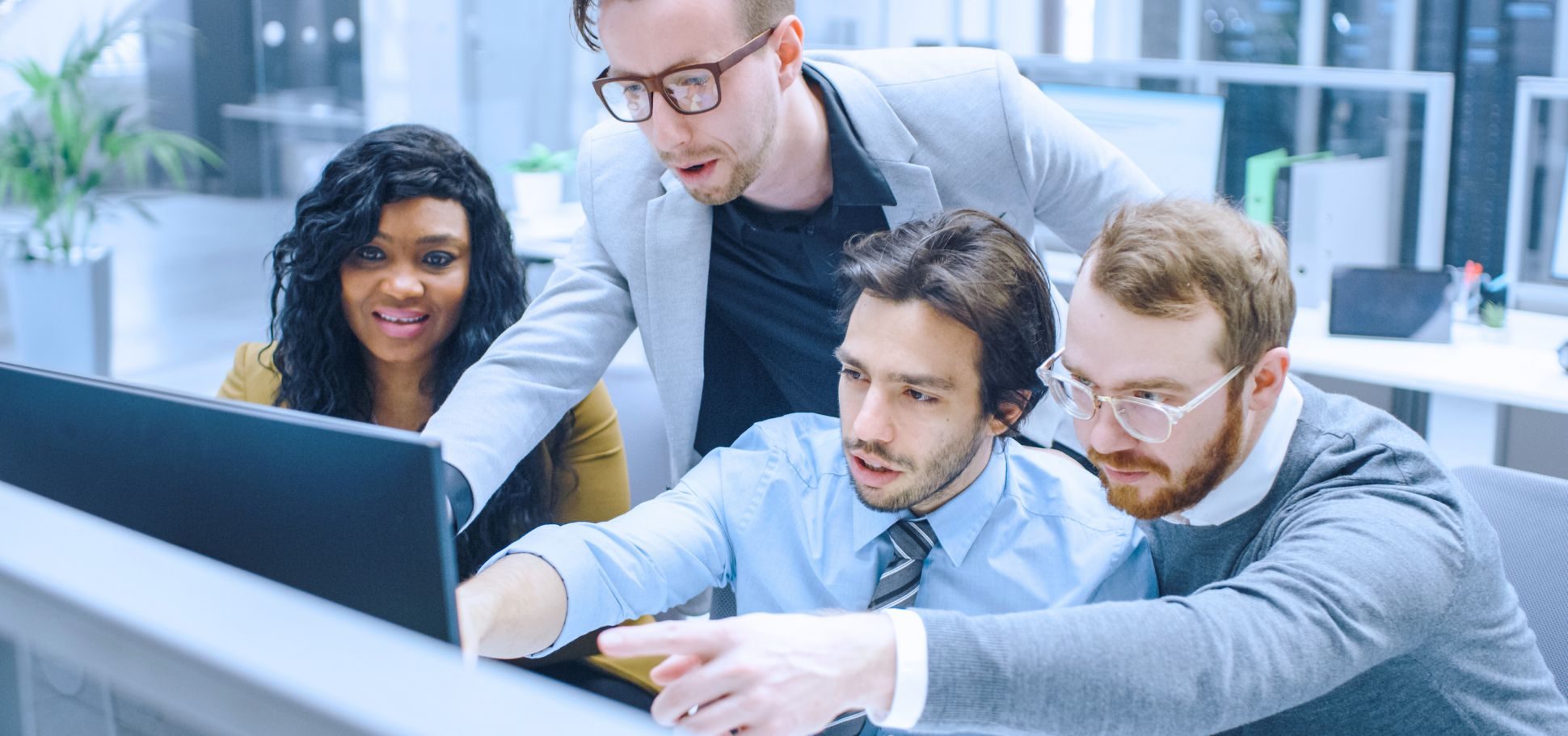 A group of colleagues point to their computer