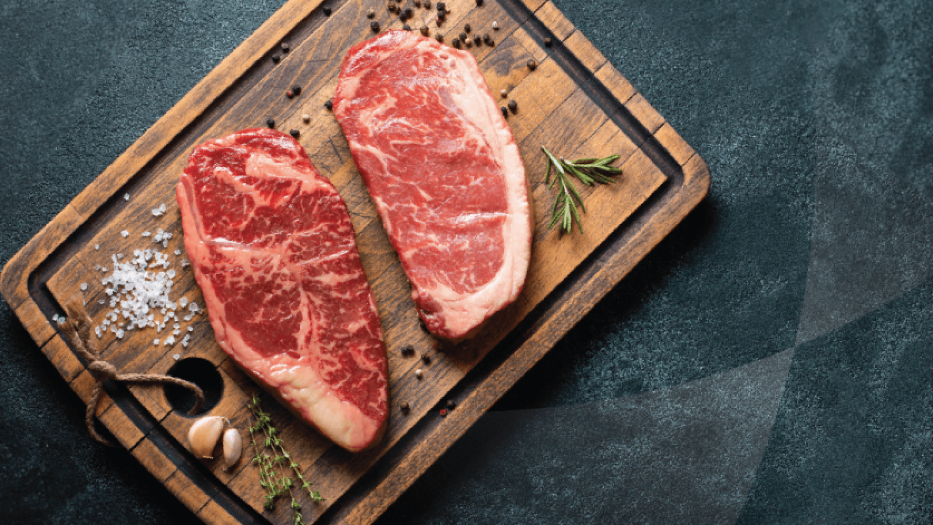 two steaks on a wooden cutting board surrounded by black pepper and thyme